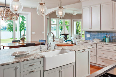 Example of a mid-sized transitional l-shaped medium tone wood floor eat-in kitchen design in Other with a farmhouse sink, recessed-panel cabinets, green cabinets, quartzite countertops, blue backsplash, glass tile backsplash and an island