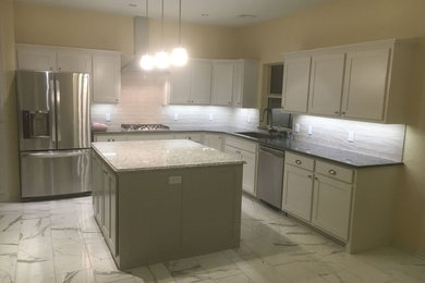 Large trendy l-shaped marble floor eat-in kitchen photo in Orange County with an undermount sink, shaker cabinets, white cabinets, granite countertops, white backsplash, stainless steel appliances and an island