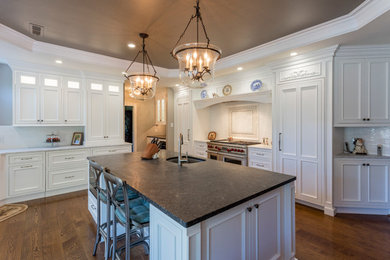 Inspiration for a large timeless u-shaped dark wood floor eat-in kitchen remodel in Philadelphia with a farmhouse sink, recessed-panel cabinets, white cabinets, marble countertops, white backsplash, ceramic backsplash, paneled appliances and an island