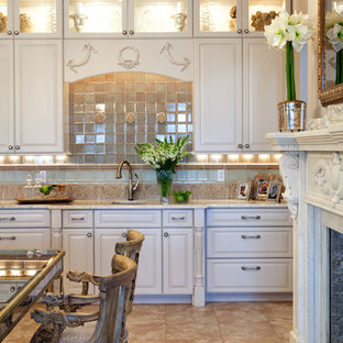 Foto di una grande cucina tradizionale con lavello a tripla vasca, ante con bugna sagomata, ante bianche, top in granito, paraspruzzi beige, paraspruzzi con piastrelle in pietra, elettrodomestici da incasso e pavimento in travertino
