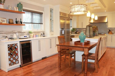 Example of a mid-sized transitional l-shaped medium tone wood floor and brown floor eat-in kitchen design in Orange County with shaker cabinets, white cabinets, multicolored backsplash, matchstick tile backsplash, stainless steel appliances, an island, an undermount sink and quartzite countertops