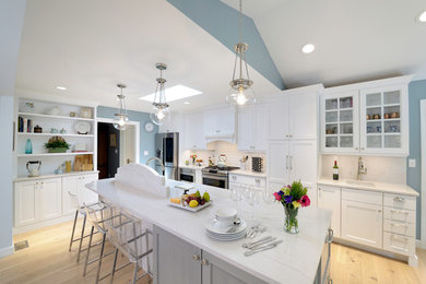 Eat-in kitchen - large transitional l-shaped eat-in kitchen idea in St Louis with a farmhouse sink, shaker cabinets, white cabinets, quartz countertops, white backsplash, stainless steel appliances, an island and porcelain backsplash
