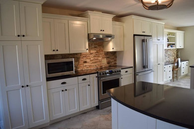 Example of a mid-sized transitional single-wall ceramic tile eat-in kitchen design in Wichita with shaker cabinets, white cabinets, brown backsplash, stone tile backsplash, stainless steel appliances, an island and granite countertops