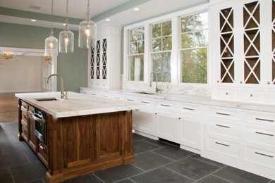 Large transitional galley marble floor, black floor and tray ceiling kitchen pantry photo in New York with an undermount sink, recessed-panel cabinets, white cabinets, marble countertops, white backsplash, marble backsplash, paneled appliances, an island and white countertops