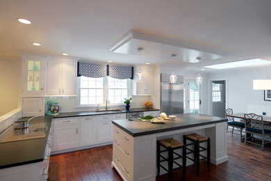 Open concept kitchen - large transitional l-shaped medium tone wood floor open concept kitchen idea in Philadelphia with an undermount sink, flat-panel cabinets, white cabinets, granite countertops, white backsplash, ceramic backsplash, stainless steel appliances and an island