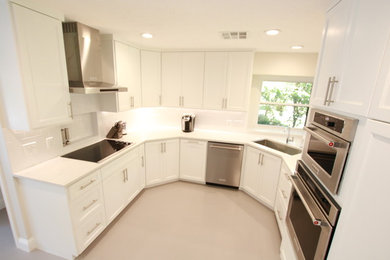 Example of a large trendy u-shaped concrete floor and gray floor eat-in kitchen design in Houston with an undermount sink, shaker cabinets, white cabinets, granite countertops, white backsplash, porcelain backsplash, stainless steel appliances and an island