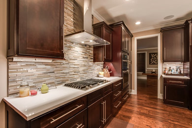 Example of a mid-sized trendy u-shaped medium tone wood floor open concept kitchen design in Other with a double-bowl sink, recessed-panel cabinets, dark wood cabinets, solid surface countertops, multicolored backsplash, matchstick tile backsplash, stainless steel appliances and a peninsula