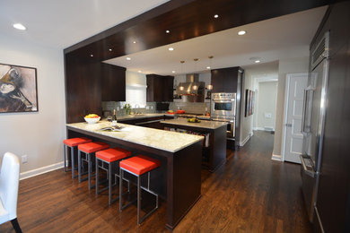 Eat-in kitchen - large contemporary u-shaped dark wood floor eat-in kitchen idea in Milwaukee with an undermount sink, flat-panel cabinets, dark wood cabinets, granite countertops, gray backsplash, glass tile backsplash, stainless steel appliances and an island