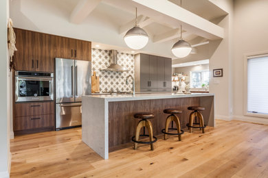 Inspiration for a contemporary l-shaped medium tone wood floor and brown floor open concept kitchen remodel in Edmonton with an undermount sink, flat-panel cabinets, medium tone wood cabinets, multicolored backsplash, stainless steel appliances, an island and gray countertops
