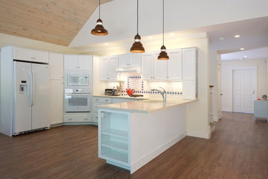 Example of a mid-sized classic u-shaped dark wood floor kitchen pantry design in Boston with white cabinets, white backsplash, ceramic backsplash, white appliances, a drop-in sink, shaker cabinets, laminate countertops and a peninsula