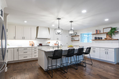 Example of a large classic u-shaped medium tone wood floor eat-in kitchen design in Other with shaker cabinets, white cabinets, quartz countertops, white backsplash, an island and gray countertops