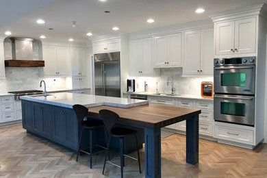 Large transitional l-shaped light wood floor and brown floor eat-in kitchen photo in New York with an undermount sink, beaded inset cabinets, white cabinets, quartz countertops, multicolored backsplash, marble backsplash, stainless steel appliances, an island and white countertops