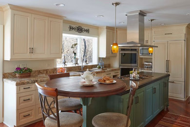 Large transitional l-shaped medium tone wood floor and brown floor kitchen photo in Chicago with an undermount sink, raised-panel cabinets, beige cabinets, granite countertops, paneled appliances and an island