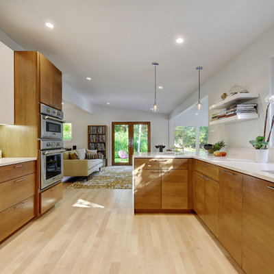 Inspiration for a large mid-century modern galley light wood floor eat-in kitchen remodel in Austin with an undermount sink, flat-panel cabinets, medium tone wood cabinets, quartz countertops, white backsplash, glass sheet backsplash and stainless steel appliances