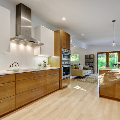 Eat-in kitchen - large 1960s galley light wood floor eat-in kitchen idea in Austin with an undermount sink, flat-panel cabinets, medium tone wood cabinets, quartz countertops, white backsplash, glass sheet backsplash and stainless steel appliances