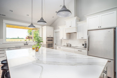 Large transitional l-shaped medium tone wood floor and beige floor open concept kitchen photo in Portland with an undermount sink, shaker cabinets, white cabinets, marble countertops, white backsplash, subway tile backsplash, stainless steel appliances, an island and white countertops
