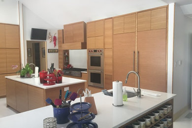 ダラスにある広いモダンスタイルのおしゃれなキッチン (ドロップインシンク、フラットパネル扉のキャビネット、中間色木目調キャビネット、クオーツストーンカウンター、白いキッチンパネル、シルバーの調理設備) の写真