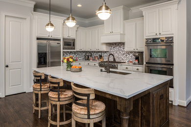 Large farmhouse l-shaped kitchen/diner in Dallas with a submerged sink, recessed-panel cabinets, white cabinets, engineered stone countertops, multi-coloured splashback, ceramic splashback, stainless steel appliances, dark hardwood flooring, an island, brown floors and white worktops.