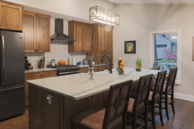 Example of a transitional single-wall medium tone wood floor and brown floor open concept kitchen design in Cleveland with a farmhouse sink, shaker cabinets, medium tone wood cabinets, quartzite countertops, white backsplash, ceramic backsplash, black appliances, an island and white countertops