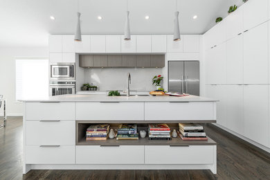 Mid-sized trendy u-shaped brown floor and dark wood floor eat-in kitchen photo in Ottawa with an undermount sink, white cabinets, stainless steel appliances, an island, flat-panel cabinets, quartz countertops, white backsplash, porcelain backsplash and gray countertops