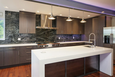 Ejemplo de cocina de estilo americano abierta con electrodomésticos de acero inoxidable, suelo de madera clara y una isla
