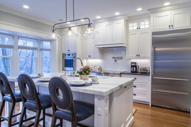 Inspiration for a mid-sized timeless single-wall medium tone wood floor and brown floor enclosed kitchen remodel in Other with an undermount sink, shaker cabinets, white cabinets, quartzite countertops, white backsplash, ceramic backsplash, stainless steel appliances, an island and white countertops