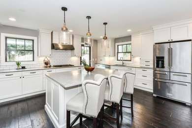 Eat-in kitchen - transitional l-shaped dark wood floor and brown floor eat-in kitchen idea in DC Metro with a drop-in sink, recessed-panel cabinets, white cabinets, quartz countertops, white backsplash, subway tile backsplash, stainless steel appliances, an island and gray countertops