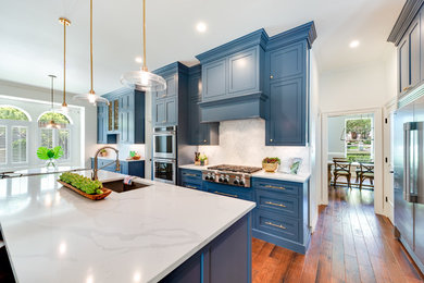 Large transitional l-shaped medium tone wood floor and brown floor open concept kitchen photo in Dallas with an undermount sink, shaker cabinets, blue cabinets, marble countertops, gray backsplash, marble backsplash, stainless steel appliances, an island and white countertops