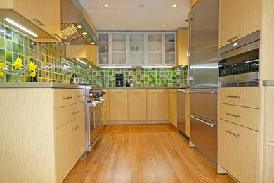 Example of a mid-sized transitional galley medium tone wood floor enclosed kitchen design in Chicago with an undermount sink, flat-panel cabinets, light wood cabinets, concrete countertops, green backsplash and stainless steel appliances