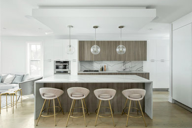 This is an example of a contemporary l-shaped kitchen in Chicago with a submerged sink, flat-panel cabinets, grey cabinets, white splashback, stainless steel appliances, medium hardwood flooring, an island, brown floors and white worktops.