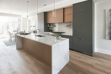 Mid-sized trendy galley medium tone wood floor and beige floor open concept kitchen photo in Other with an undermount sink, flat-panel cabinets, gray cabinets, quartz countertops, white backsplash, quartz backsplash, paneled appliances, an island and white countertops