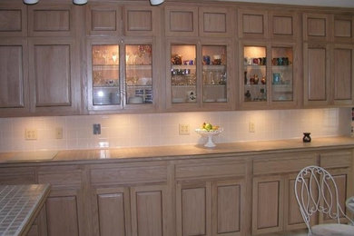 他の地域にあるトラディショナルスタイルのおしゃれなアイランドキッチン (淡色木目調キャビネット、タイルカウンター、セラミックタイルのキッチンパネル) の写真