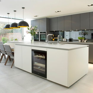 Design ideas for a medium sized contemporary single-wall kitchen/diner in London with a submerged sink, flat-panel cabinets, white cabinets, mirror splashback, an island and grey floors.