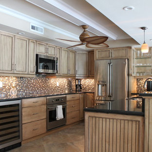 This is an example of a mid-sized tropical u-shaped eat-in kitchen in Miami with an undermount sink, medium wood cabinets, granite benchtops, multi-coloured splashback, glass tile splashback, stainless steel appliances, travertine floors, with island and louvered cabinets.
