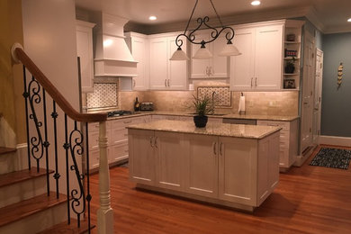 Example of a large transitional l-shaped medium tone wood floor and brown floor open concept kitchen design in Other with an undermount sink, shaker cabinets, white cabinets, granite countertops, beige backsplash, subway tile backsplash, stainless steel appliances, an island and beige countertops