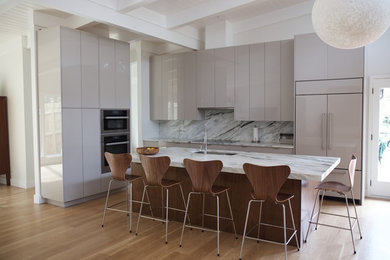 Medium sized contemporary l-shaped open plan kitchen in Atlanta with a submerged sink, flat-panel cabinets, grey cabinets, integrated appliances, light hardwood flooring, an island, marble worktops, white splashback, marble splashback and brown floors.