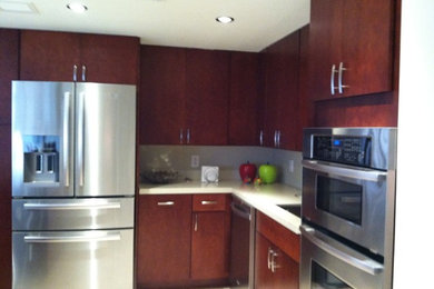 Example of a mid-sized transitional l-shaped open concept kitchen design in Miami with an undermount sink, flat-panel cabinets, dark wood cabinets, quartz countertops, stainless steel appliances and a peninsula