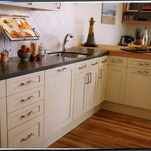 Inspiration for a mid-sized traditional galley kitchen in Auckland with a single-bowl sink, recessed-panel cabinets, white cabinets, concrete benchtops, white splashback, ceramic splashback, panelled appliances, medium hardwood floors, multiple islands, orange floor and grey benchtop.