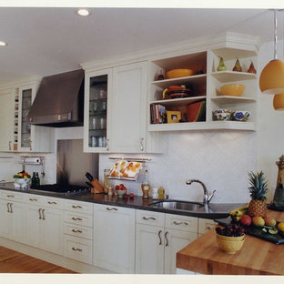 Mid-sized traditional galley kitchen in Auckland with a single-bowl sink, recessed-panel cabinets, white cabinets, concrete benchtops, white splashback, ceramic splashback, panelled appliances, medium hardwood floors, multiple islands, orange floor and grey benchtop.