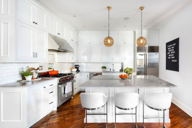 Transitional l-shaped medium tone wood floor kitchen photo in New York with an undermount sink, recessed-panel cabinets, white cabinets, white backsplash, subway tile backsplash, stainless steel appliances, an island and gray countertops