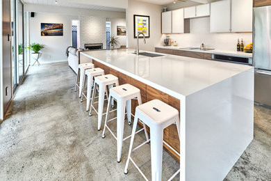 Contemporary kitchen in San Francisco with a single-bowl sink, flat-panel cabinets, engineered stone countertops, metro tiled splashback, stainless steel appliances and concrete flooring.