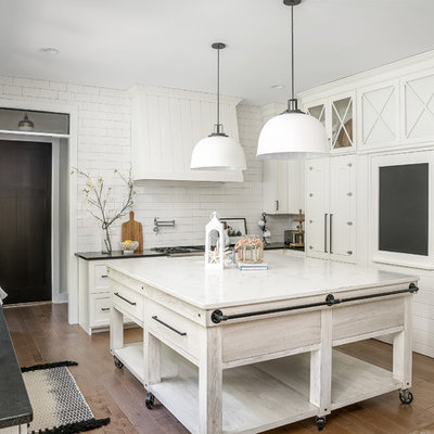 Kitchen - country u-shaped medium tone wood floor and brown floor kitchen idea in Chicago with a farmhouse sink, shaker cabinets, white cabinets, white backsplash, subway tile backsplash and an island