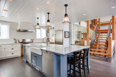 Farmhouse u-shaped porcelain tile open concept kitchen photo in Calgary with a farmhouse sink, beaded inset cabinets, white cabinets, quartz countertops, white backsplash, subway tile backsplash, stainless steel appliances and an island