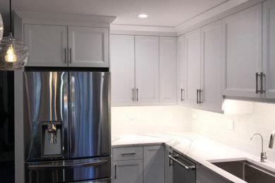Example of a mid-sized transitional l-shaped dark wood floor enclosed kitchen design in Chicago with an undermount sink, recessed-panel cabinets, white cabinets, quartz countertops, glass tile backsplash, stainless steel appliances and an island