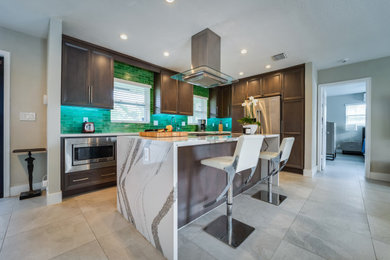 Foto på ett mellanstort funkis flerfärgad kök, med en undermonterad diskho, luckor med infälld panel, skåp i mellenmörkt trä, bänkskiva i kvarts, grönt stänkskydd, stänkskydd i glaskakel, rostfria vitvaror, klinkergolv i porslin, en köksö och grått golv