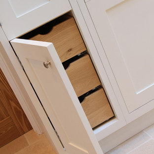 Inspiration for an expansive contemporary u-shaped open plan kitchen in Hampshire with a farmhouse sink, shaker cabinets, white cabinets, granite benchtops, black splashback, black appliances, limestone floors and a peninsula.