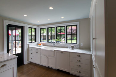 Inspiration for a timeless u-shaped medium tone wood floor kitchen remodel in Boston with a farmhouse sink, recessed-panel cabinets, white cabinets, quartz countertops, blue backsplash, glass tile backsplash, stainless steel appliances and an island