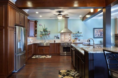 Example of a large arts and crafts u-shaped dark wood floor and brown floor kitchen design in Orlando with a farmhouse sink, flat-panel cabinets, dark wood cabinets, granite countertops, stainless steel appliances and an island