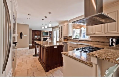 Open concept kitchen - large traditional u-shaped travertine floor and beige floor open concept kitchen idea in Montreal with a farmhouse sink, raised-panel cabinets, white cabinets, granite countertops, beige backsplash, stone tile backsplash, stainless steel appliances and an island