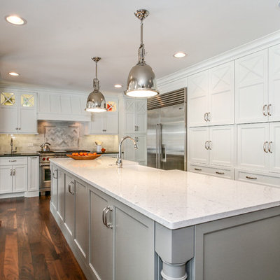 Inspiration for a large timeless u-shaped dark wood floor and brown floor kitchen remodel in Chicago with a farmhouse sink, shaker cabinets, white cabinets, white backsplash, stainless steel appliances, quartzite countertops and an island